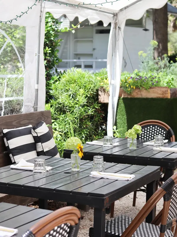 A patio table set beside a planter of flowers