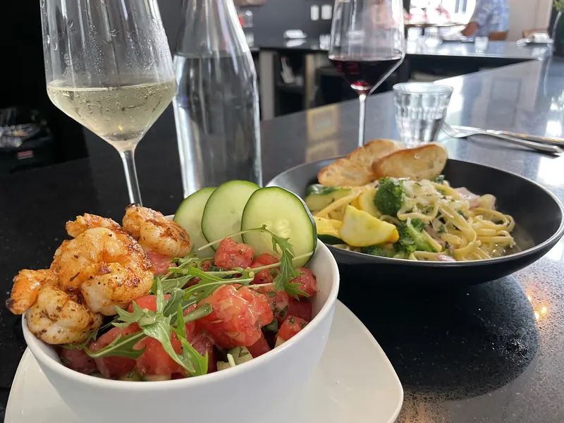 A shrimp salad and a pasta dish served with white wine