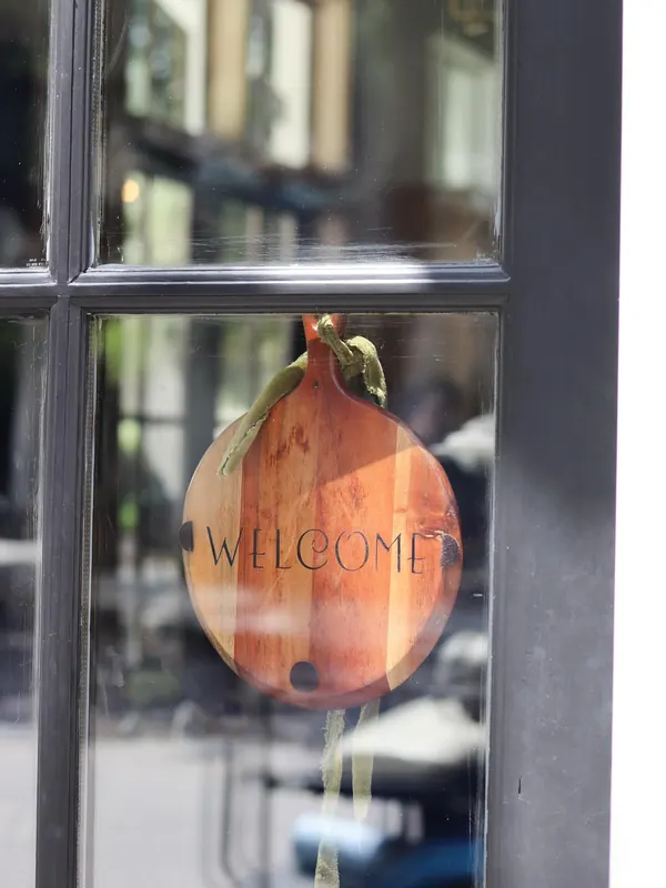 A painted wooden tomato sign reading Welcome in the window